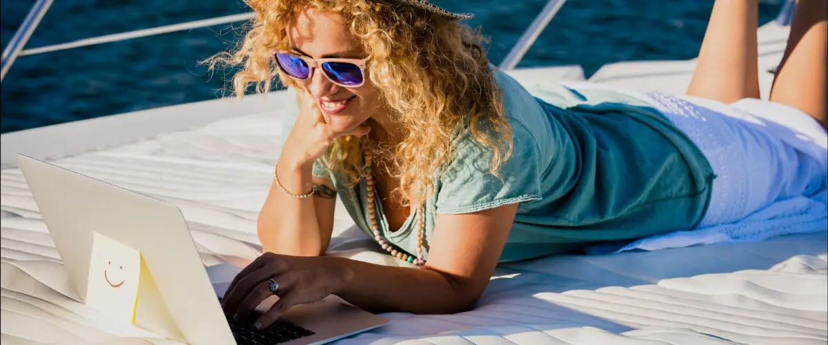 mulher com óculos escuros deitada em um barco trabalhando como nômade digital